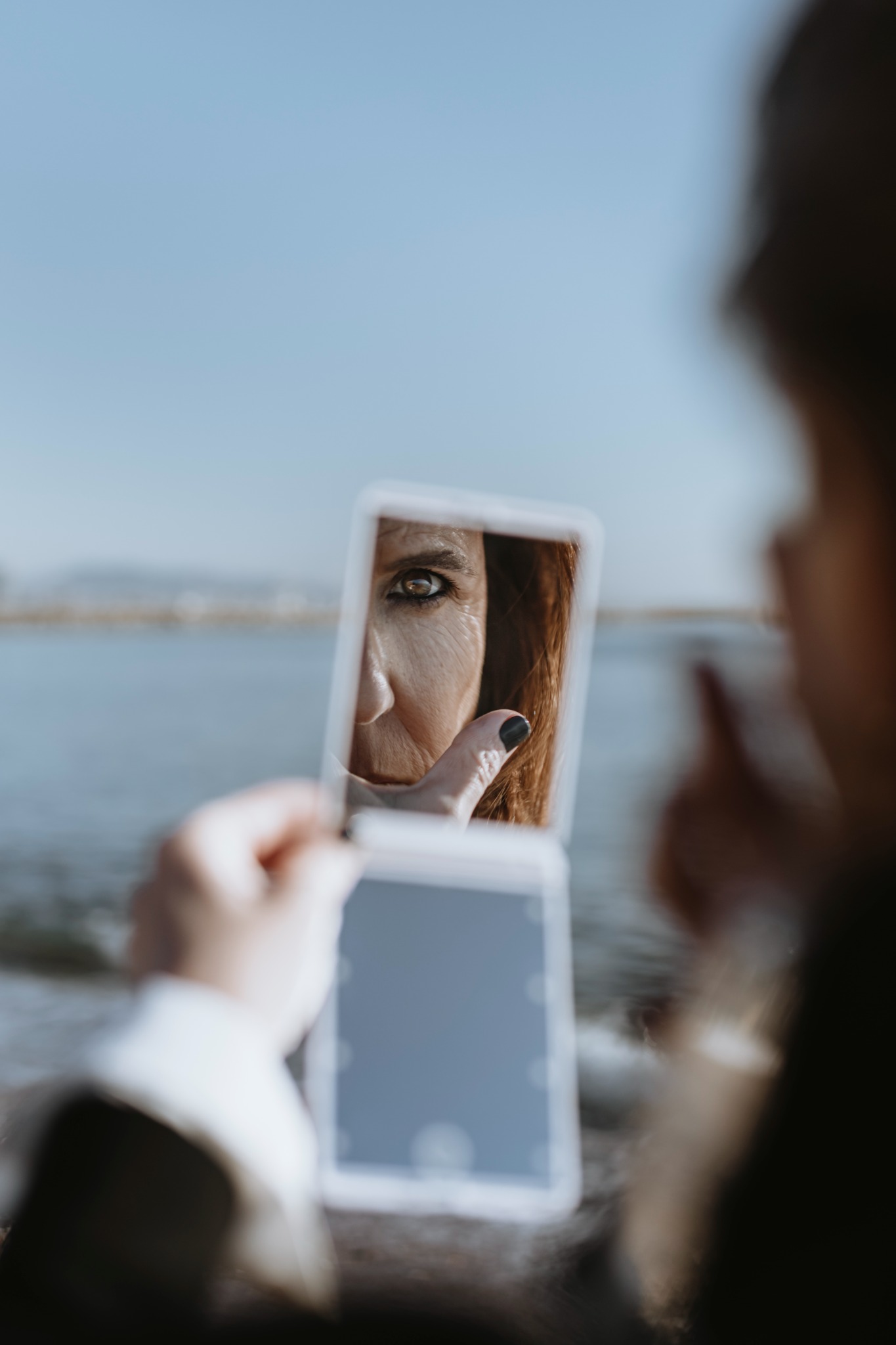 El rostro de Cris reflejado en un espejo junto al mar
